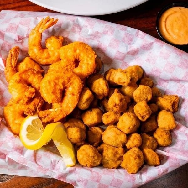 Fried shrimp and fried okra with lemon wedges and a side of dipping sauce.