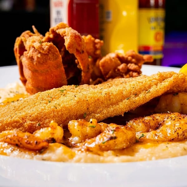 Fried fish and shrimp with grits, topped with a lemon wedge and fried crab.