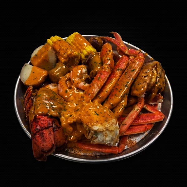 A metal platter overflowing with a seafood boil of lobster, crab legs, shrimp, corn, and potatoes.